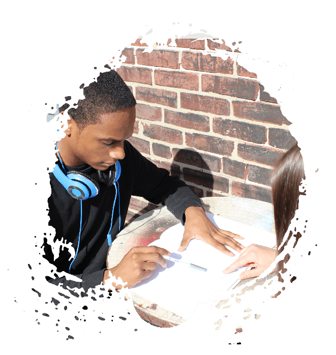 A boy with headphones looking at papers on the table