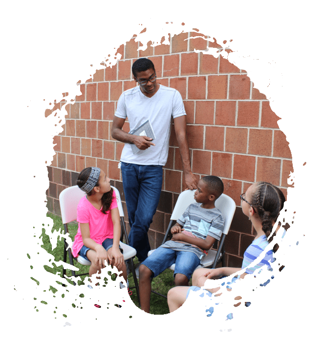 A group of people sitting around in front of a brick wall.